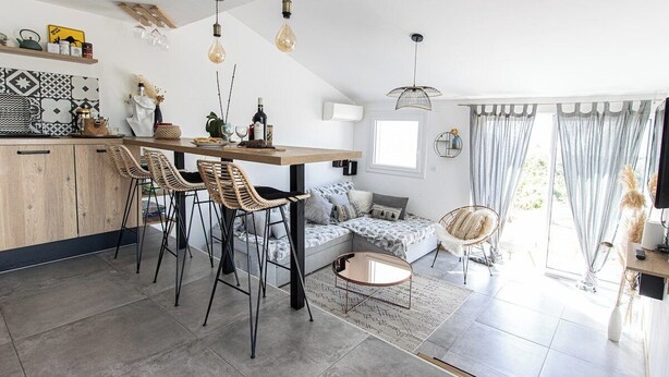 Eine moderne Küche mit einer Holztheke, Barhocker und Pendelleuchten.