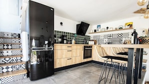 Eine moderne Küche mit einem schwarzen Kühlschrank, Holzschränken und einer gefliesten Spritzschutzwand.