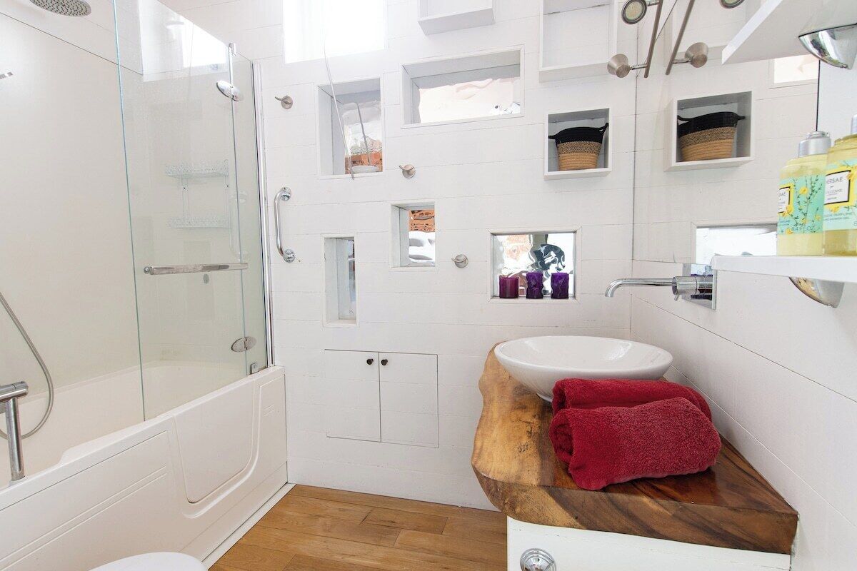 A modern bathroom with a glass-enclosed shower, a wooden vanity, and a white sink.