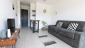 Uma sala de estar com sofá, mesa de centro, TV e um espaço de jantar com cadeiras e mesa.