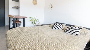 Quarto com cama, almofadas, mesinha e enfeites na parede.