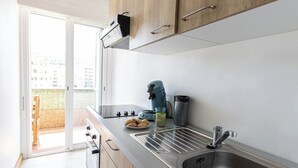 Cozinha moderna com pia de aço inoxidável, chaleira e cafeteira sobre o balcão.