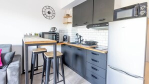 A modern kitchen with a central island, black cabinets, a white refrigerator, and a clock on the wall. - "I Cavadilli" – Peaceful Studio | by Efficios (Propriano)