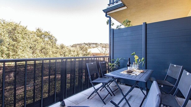 A balcony with a table and chairs, a potted plant, and a view of trees and hills. - "I Cavadilli" – Peaceful Studio | by Efficios (Propriano)