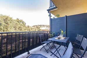 A balcony with a table and chairs, a potted plant, and a view of trees and hills. - "I Cavadilli" – Peaceful Studio | by Efficios (Propriano)