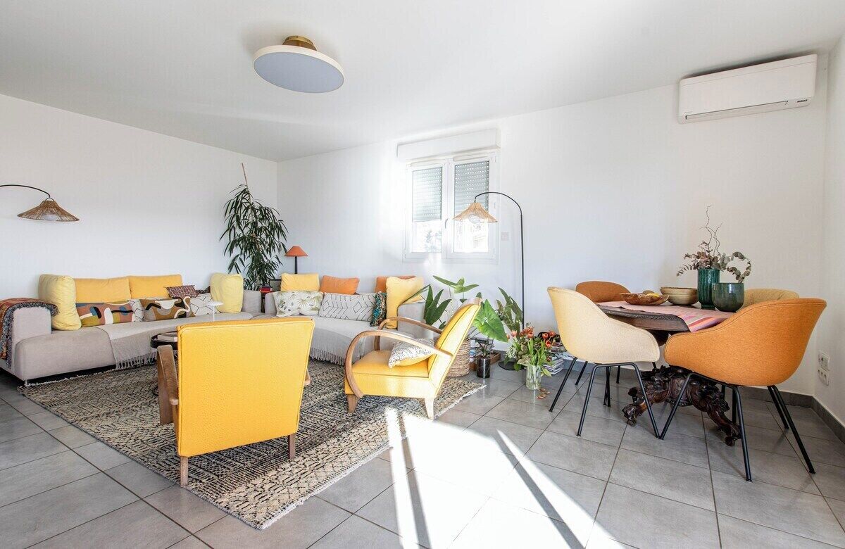 Una sala de estar moderna con un sofá, sillas, una mesa de comedor y un ventanal grande.