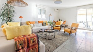 A modern living room with a sofa, armchairs, a coffee table, and a dining area. - "I Sanguinari" – 2BR Sea View Apt | by Efficios (Ajaccio)