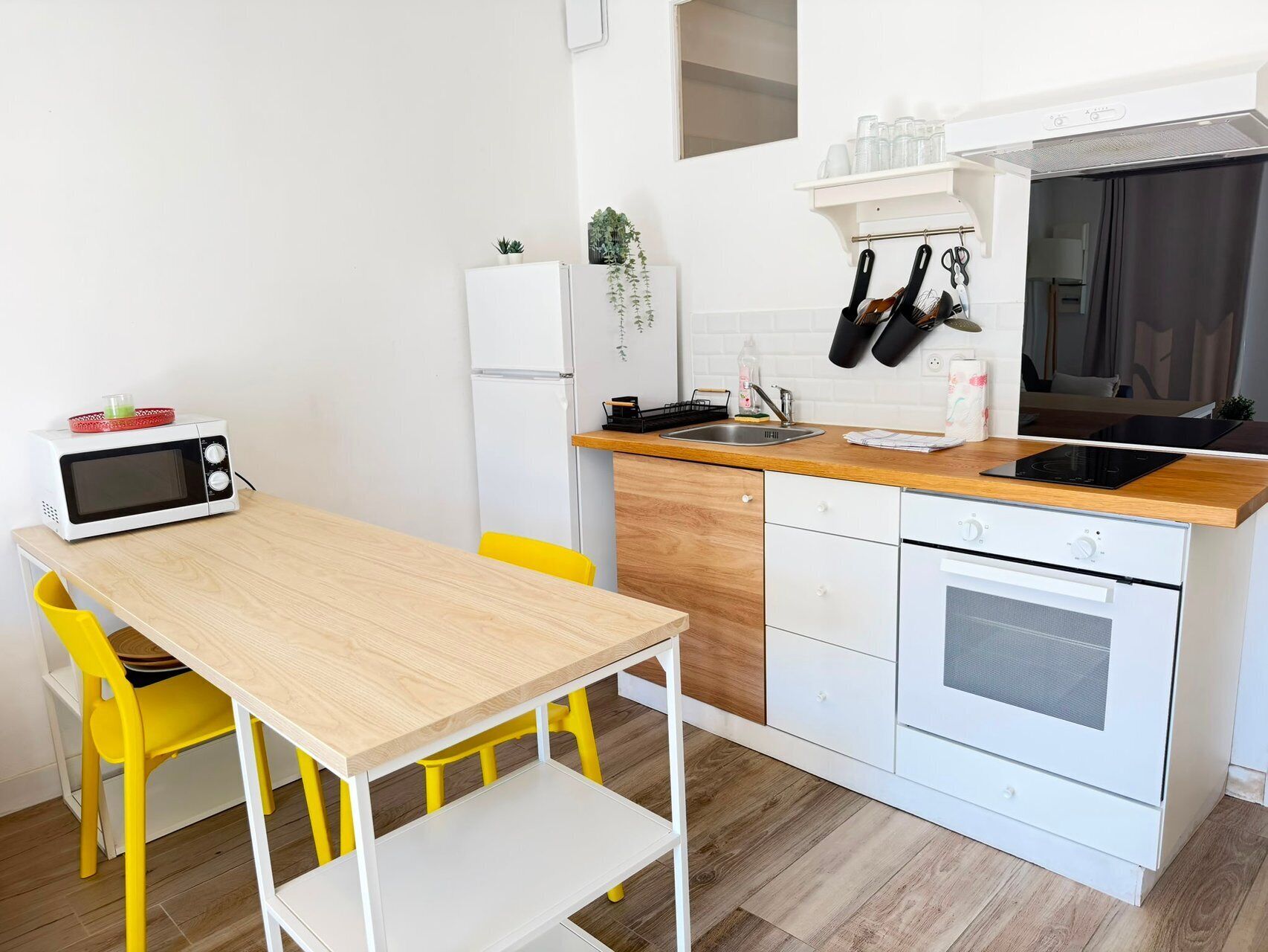 Una cocina compacta con microondas, fregadero, estufa y un refrigerador pequeño.