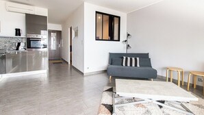 En modern lägenhet med ett kök, en grå soffa och ett litet träbord.