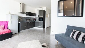 Ett modernt kök med en köksö i mitten, en matplats med en soffa och ett stort fönster.