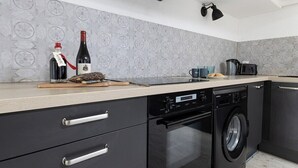 Una cocina moderna con lavavajillas, horno y una botella de vino en la encimera.