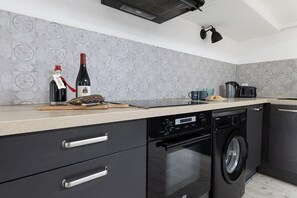 Eine moderne Küche mit Geschirrspüler, Backofen und einer Weinflasche auf der Arbeitsfläche.