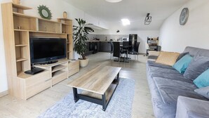 Una sala de estar moderna con una televisión de pantalla plana, un mueble de entretenimiento de madera, un sofá gris y una mesa de centro.