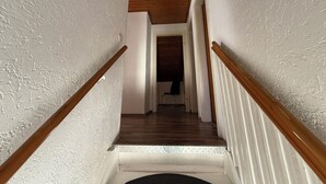 A narrow staircase with wooden handrails, white walls, and a wooden ceiling. - Apartment for up to 4 people | Kitchen & bathroom | Pension NH (Osterholz-Scharmbeck)