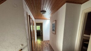 A hallway with wooden flooring, a ceiling fan, and a door leading to a room. - Apartment for up to 4 people | Kitchen & bathroom | Pension NH (Osterholz-Scharmbeck)