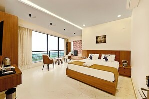 A modern hotel room with a large bed, a desk, and a view of the sea. - PN Stays (Ponneri)
