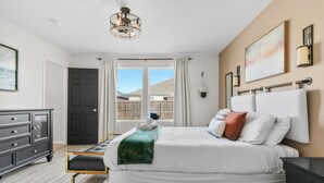 Een slaapkamer met een groot bed, een kaptafel, een kroonluchter en uitzicht op het omliggende landschap.