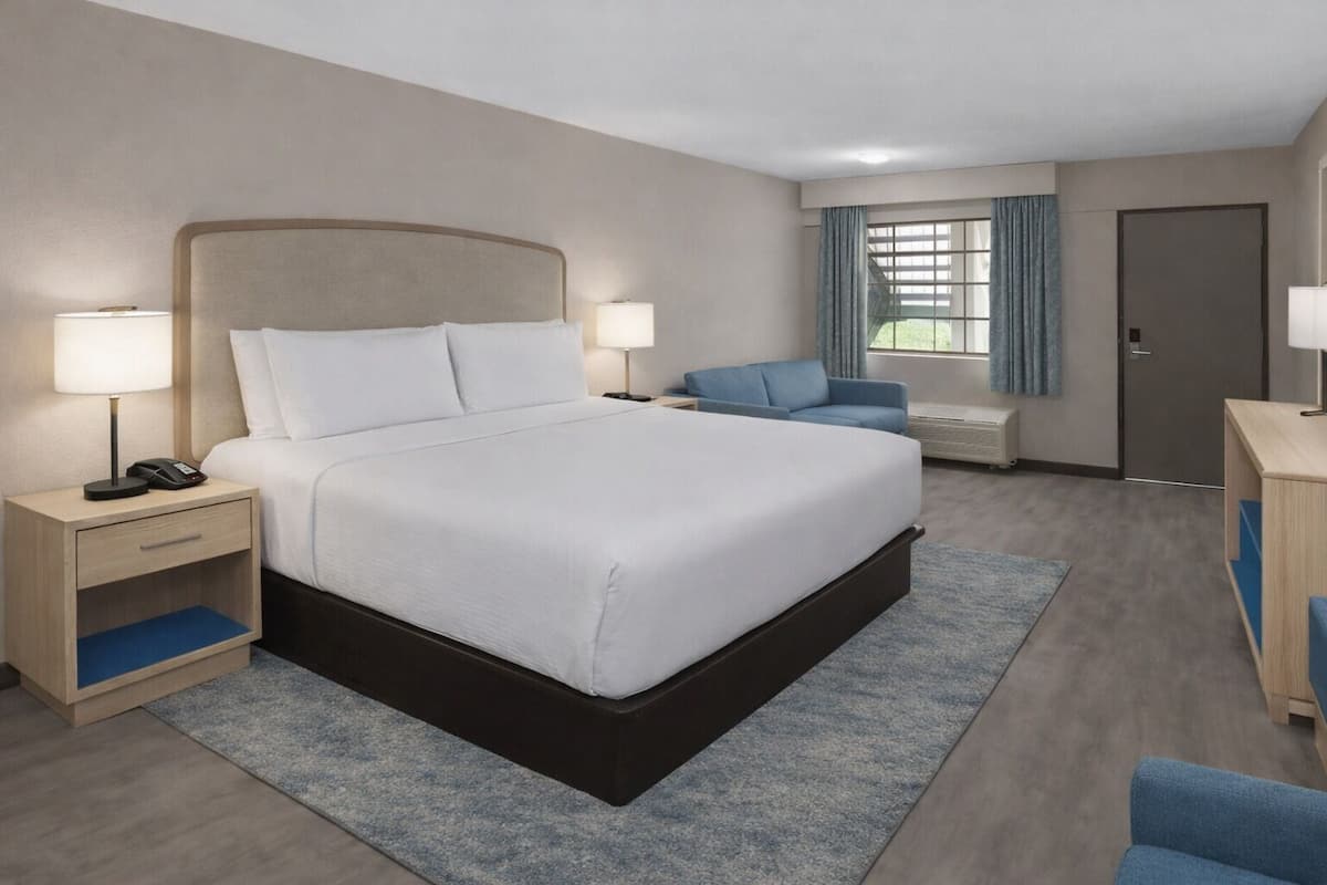 Een hotelkamer met een bed, nachtkastjes, een bureau, een stoel en een raam met gordijnen.
