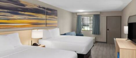 Quarto de hotel com duas camas, uma escrivaninha, televisão e um quadro na parede.