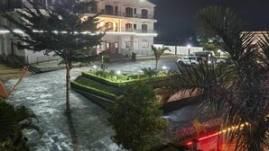 A multi-story building with a well-lit entrance and a landscaped area with a water feature. - MANGORO HOTEL (Moramanga)