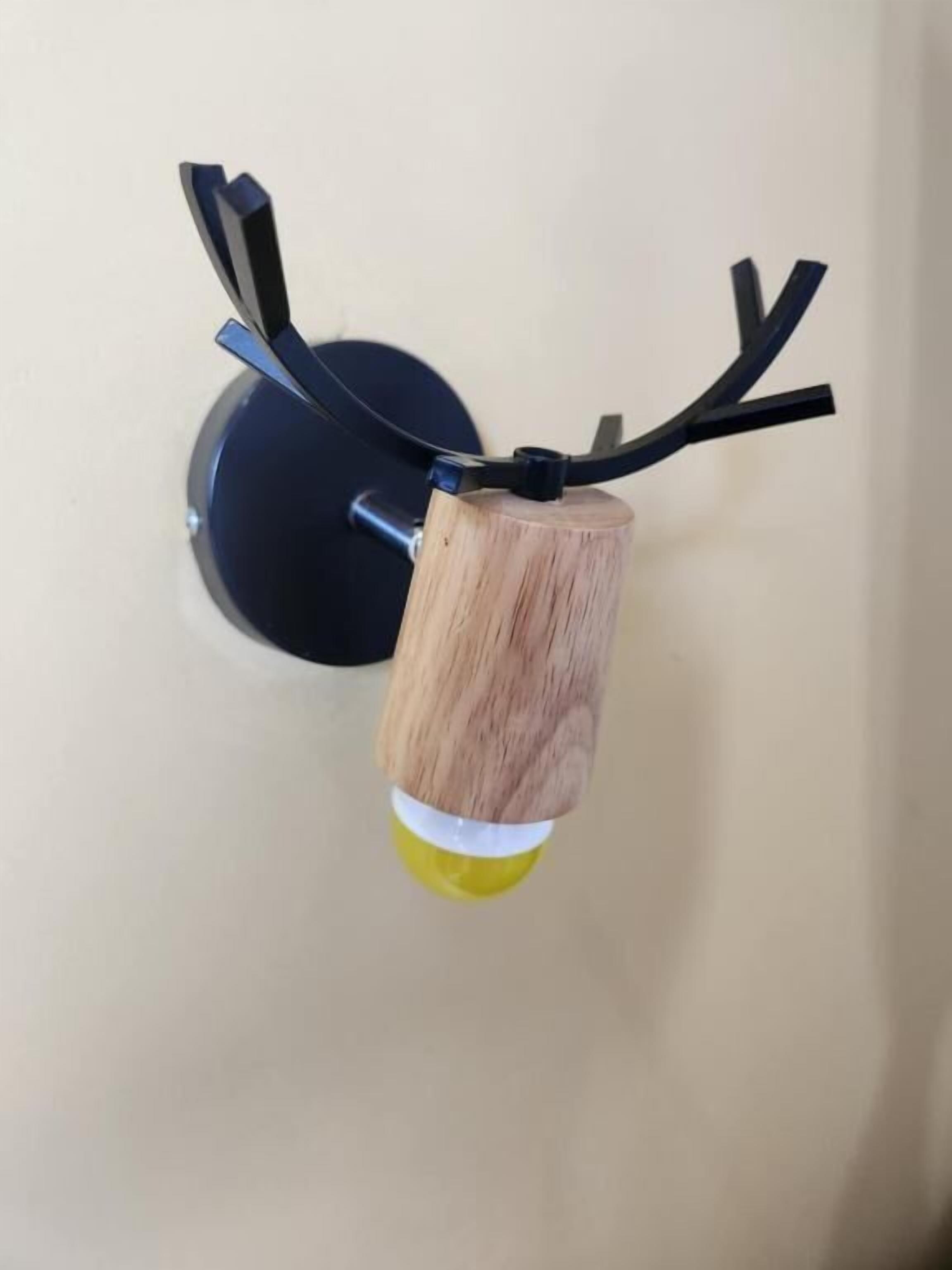 A wall-mounted light fixture with a wooden base and a circular metal plate.