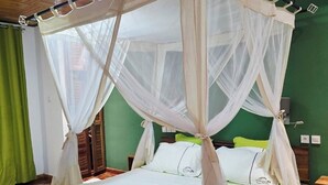 A bed with a canopy, green walls, and a wooden floor. - MANGORO HOTEL (Moramanga)
