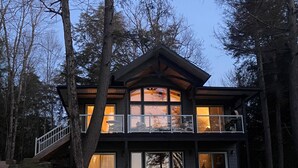 Una casa a due piani con un balcone, ampie finestre e una scala che conduce all'ingresso.