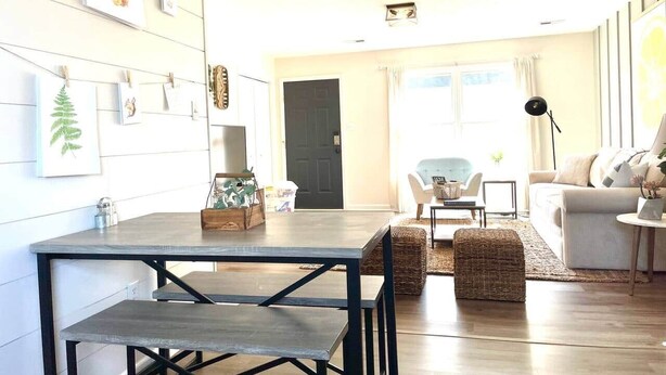 Una sala de estar moderna con comedor, que incluye una mesa de madera, sillas, un sofá y una mesa auxiliar.