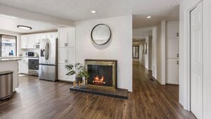 Una cocina moderna con chimenea integrada, armarios blancos y piso de madera.