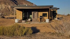A modern house with a covered patio, outdoor seating, and a view of a desert landscape.