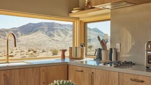 A kitchen with wooden cabinets, a sink, and a window with a desert view.