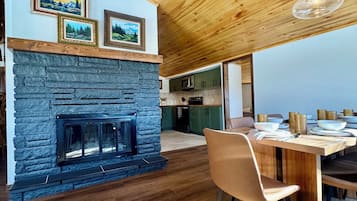 Eine moderne Küche mit Steinofen, Holzboden und einem Essbereich mit Tisch und Stühlen.