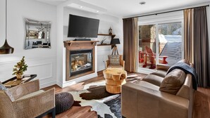 Een moderne woonkamer met een open haard, een televisie en uitzicht op de omgeving.