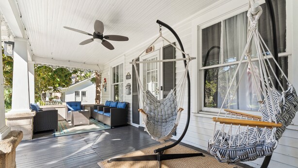 Een veranda met een plafondventilator, twee hangmatten en tuinmeubilair.