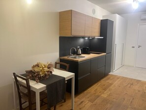 A compact kitchen with a wooden countertop, a sink, and a coffee maker. There is a dining table with chairs and a vase of dried flowers. - Two-room apartment 2 min from Bocconi University and 10 from the subway (Milano)