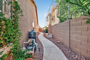 A narrow alleyway with a water tank, a concrete path, and a brick wall.