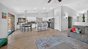 A spacious living area with a kitchen, dining area, and a ceiling fan.