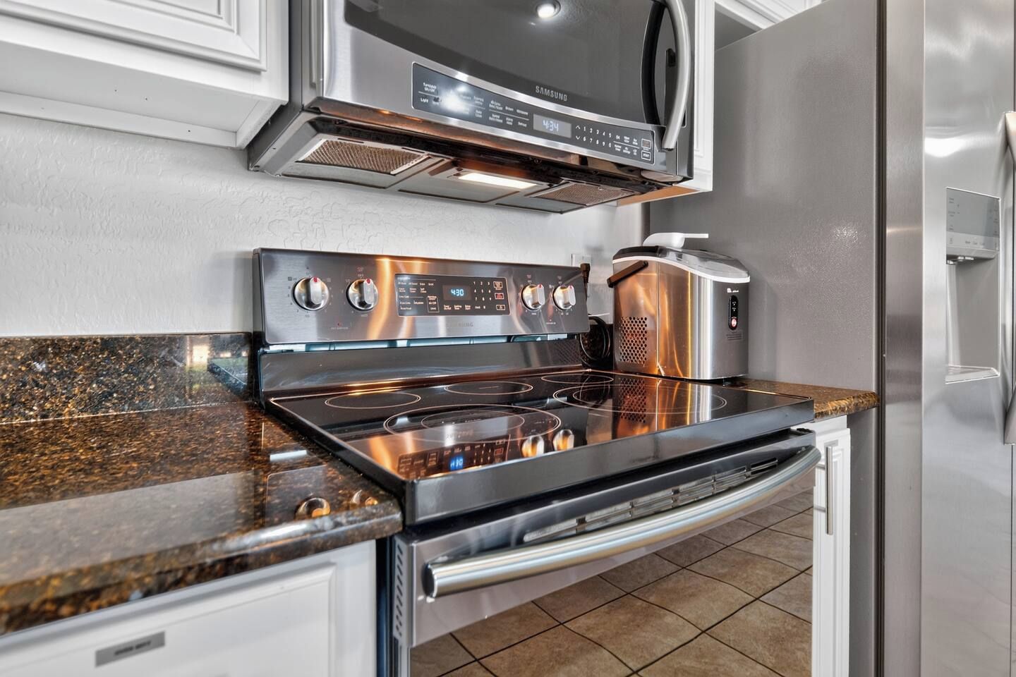 All the modern conveniences of a home kitchen - microwave, electric stove, oven, freezer, and refrigerator for easy meal prep.