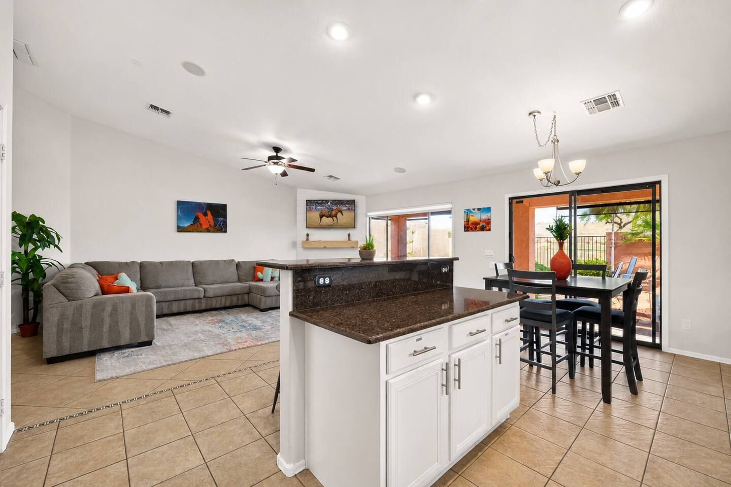 A spacious living area with a grey sofa, a kitchen island, and a dining area with a table and chairs.