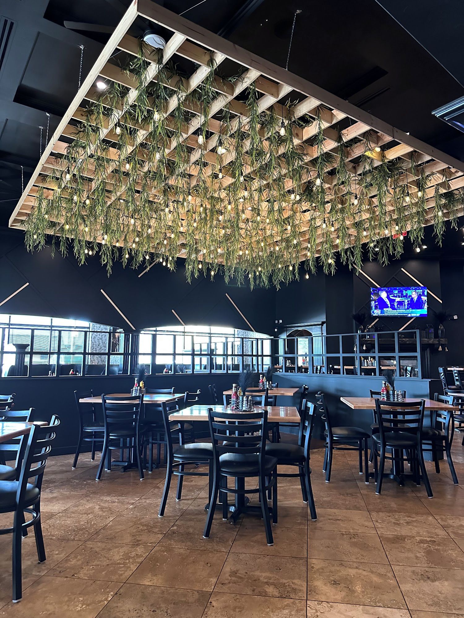 A restaurant interior with a modern design, featuring hanging plants and a bar area.
