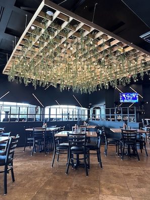 L’intérieur d’un restaurant au design moderne, agrémenté de plantes suspendues et doté d’un espace bar.