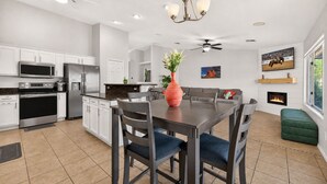 A modern kitchen with white cabinetry, stainless steel appliances, and a dining area with a table and chairs.