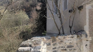 A stone building with a small outdoor seating area and a water feature. - Large mountain house for 12, comfort, peace & nature (Urdos)