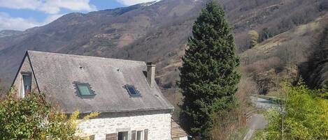 A stone house with a sloped roof, a chimney, and a small window.
