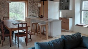 A modern kitchen with a central island, wooden dining table, and bar stools. - Large mountain house for 12, comfort, peace & nature (Urdos)