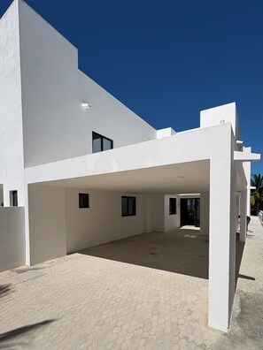 A modern white building with a covered patio area and a paved walkway.
