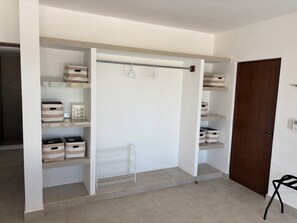 A walk-in closet with open shelving, storage bins, and a metal rack.