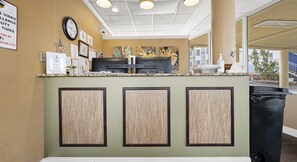 A reception area with a clock, framed certificates, and a counter with a coffee machine.