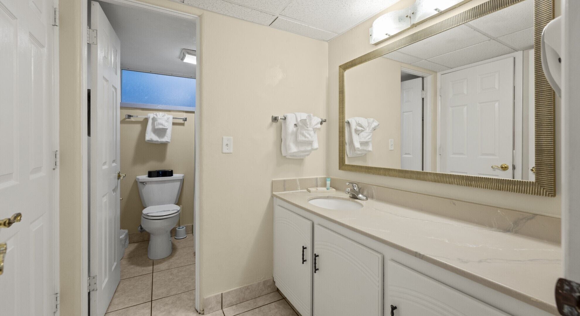 A bathroom with a toilet, sink, and mirror.