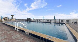 Una piscina al aire libre, sillones reclinables de piscina